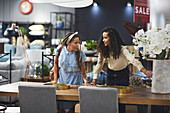Lesbian couple shopping for dining table in furniture store