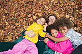 Portrait happy mother and children laying in autumn leaves