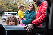 Portrait smiling boy standing outside car with family