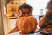 Portrait cute girl carving Halloween pumpkin at table