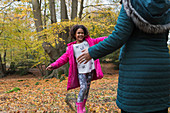 Mother and daughter playing on fallen log in autumn forest