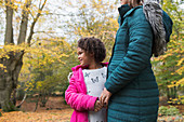 Happy daughter holding hands with mother in autumn woods