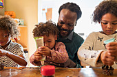 Father and children decorating cupcakes with frosting