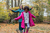 Mother and daughter balancing on fallen log in autumn woods