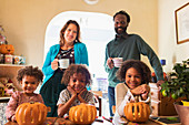 Portrait happy multiethnic family carving pumpkins