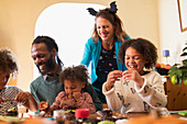 Happy family decorating Halloween cupcakes at table