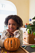 Portrait confident girl carving pumpkin at table