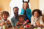 Portrait happy family decorating Halloween cupcakes at table