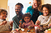 Happy multiethnic family decorating cupcakes at table