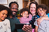 Happy multiethnic family taking selfie with camera phone