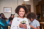 Portrait confident girl holding decorated Halloween cupcake