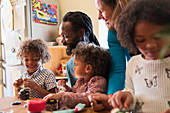 Multiethnic family decorating cupcakes at table