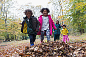 Playful family running in autumn leaves
