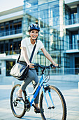 Smiling woman bike riding on urban sidewalk