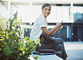 Smiling businesswoman text messaging outdoors