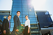 Smiling business people below highrise