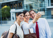Smiling business people taking self-portrait outdoors