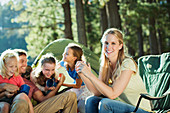 Smiling family relaxing at campsite in woods