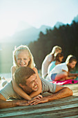 Smiling father and daughter laying on dock