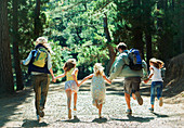 Family holding hands and running in woods