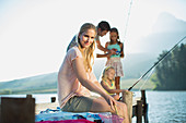 Smiling woman with family fishing on dock over lake