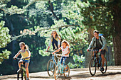 Smiling family bike riding in woods