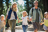 Smiling family holding hands and walking in woods