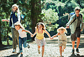 Smiling family holding hands and running in woods