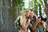 Couple looking at digital camera in woods