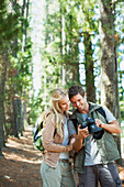 Smiling couple looking at digital camera in woods