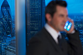 Businessman talking on cell phone in urban window at night