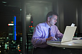 Businessman working at laptop in office at night
