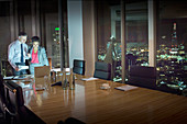 Business people at laptop in conference room at night