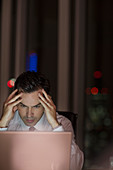 Stressed businessman working late at laptop