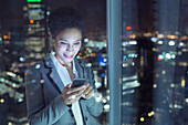 Businesswoman text messaging in urban window at night