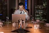 Businessman working late at laptop in conference room