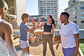 Young friends exercising and high fiving on urban rooftop