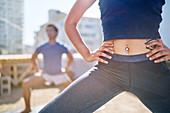 Young woman with belly piercing practicing yoga on balcony