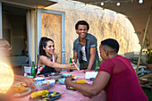 Young friends with smart phone eating lunch at patio table