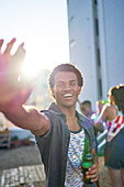 Portrait happy young man with beer on sunny balcony