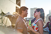 Young couple drinking beer and talking on urban rooftop
