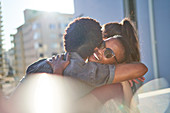 Happy young couple hugging on sunny urban balcony