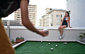 Young couple playing bocce ball on urban rooftop