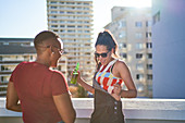 Carefree young woman dancing and drinking beer on rooftop