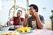 Young man eating taco lunch at patio table