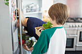 Mother and son with fresh vegetables in kitchen