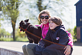 Portrait happy mother and son with dog on sunny ledge