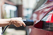 Close up woman recharging electric car