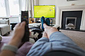 POV man on sofa with remote control watching soccer match