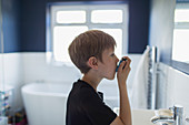 Boy with asthma using inhaler in bathroom